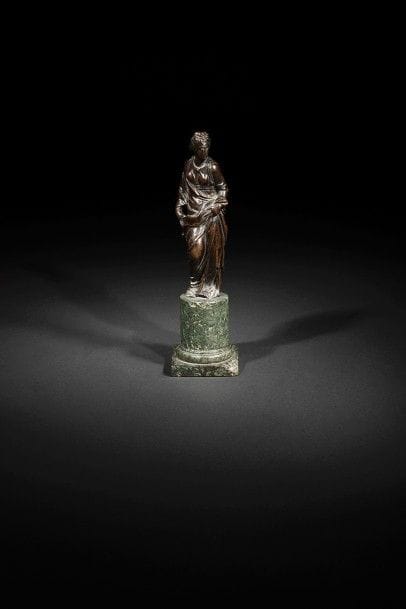Figure féminine en bronze à patine brune ; reposant sur une base circulaire en marbre vert (éclats).
Début du XVIIe siècle.
H : 30 cm
