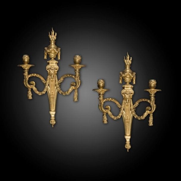 Paire d’appliques en bronze doré à deux lumières, guirlande et tête de bélier, surmontées d’un vase enflammé ; (percées pour l’électricité).
Style Louis XVI.
H : 50 cm