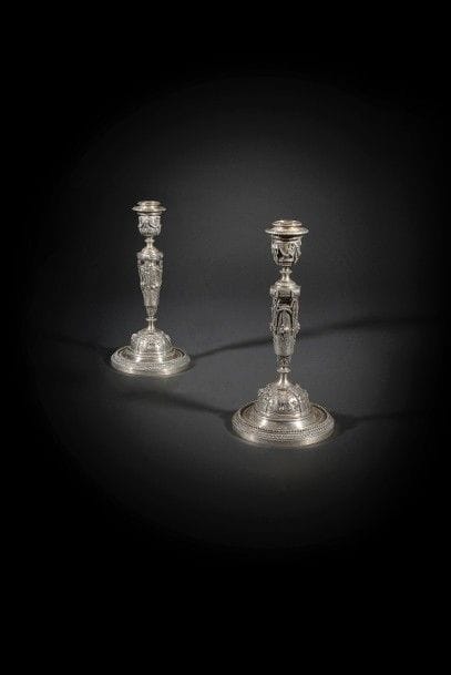 Paire de flambeaux en bronze argenté, le fût à montants feuillagés ajourés à décor de trophées et chutes de fleurs et fruits, surmonté de têtes de bélier et nœuds de ruban, la base circulaire à trophées et fleurs, frise de perles et rais de cœurs ; signée de Louis Constant Sévin (1821-1888), Désiré Attarge (1820-1878) et Ferdinand Barbedienne (1810-1892), daté 1868.
Époque Napoléon III.
H : 31,5 cm

Un flambeau identique est aujourd’hui conservé au musée d’Orsay, également conçu sous la direction de Barbedienne, dessiné par Sévin et ciselé par Attarge.