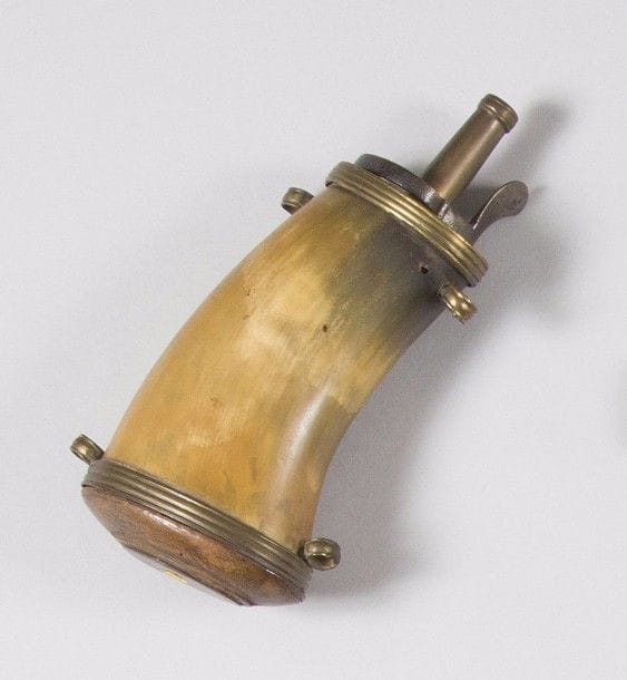 Poires à poudre
Rare poire à poudre militaire, en corne blonde, à quatre anneaux de suspente. Bec et garnitures en laiton. Fond en bois. 
B.E. XVIIIe siècle. 
