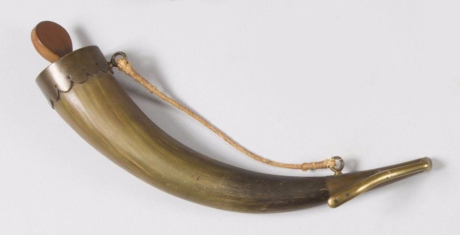 Corne à poudre d’artilleur à deux anneaux de suspente avec sa cordelette en corne claire.
Bec à grand ressort en laiton. Fond à collerette découpée à dents, avec vis en buis à corps plat. 
B.E. Fin du XVIIIe siècle. 