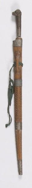 Couteau algérien dit « Flissah ». 
Monture en fer et laiton gravé. Lame à dos plat ciselé. Fourreau en bois sculpté, à quatre garnitures en fer. 
B.E. XIXe siècle. 