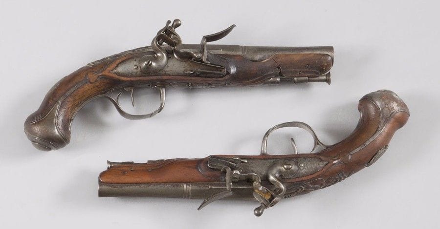 Paire de pistolet de voyage à silex.
Canons ronds à pans aux tonnerres.
Platines et chiens col de cygne à corps ronds. Garnitures en fer découpé. 
Crosse en noyer. Baguette en fanon. 
B.E. Vers 1760-1780. (Cassure au fût pour l’un des deux). 