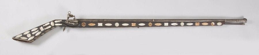 Fort fusil à silex probablement caucasien. 
Long canon tulipé à la bouche entièrement enrichi d’incrustations d’argent à décor d’entrelacs et d’une inscription à l’or en arabe. Platine à la morlaque. Fût et crosse entièrement décorés d’incrustations de nacre à décor de poissons, temples et quadrillages (manques). 
Longueur : 160 cm 
A.B.E. Milieu du XIXe siècle. 