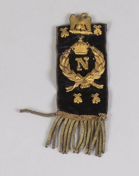 FRANCE 
Ruban dit « des débris de la Grande Armée. »
Noir, orné d’une suite d’abeilles et du « N » sous couronne entouré de lauriers, en laiton doré. 
B.E. Époque Retour des Cendres. 
