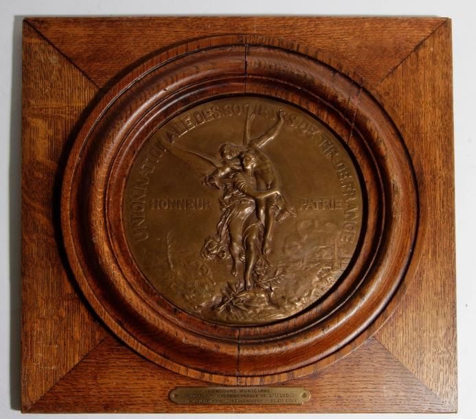 H. DUBOIS. Rome 1859. D’après A. Mercié. École française.
« Union Nationale des Sociétés de Tir de France ».
« Honneur et Patrie ».
Grande médaille ronde en bronze, signée en bas à gauche.
Diamètre : 24,4 cm
Fonte de Barbedienne.
Présentée dans un encadrement en chêne avec cartouche « Concours Municipal. Hommage de reconnaissance de l’Union à la Société de Tir Les Carabiniers de Plaisance ».
43 x 44 cm

Henri Dubois. Fils du célèbre graveur Alphée Dubois (1831-1903). Second Prix du Prix de Rome 1878. Exposé au Salon des Artistes Français dont il devint sociétaire en 1883. Médaillé de 3e classe en 1888, de 1re classe en 1892 et médaille d’argent à l’Exposition universelle de Paris en 1903.