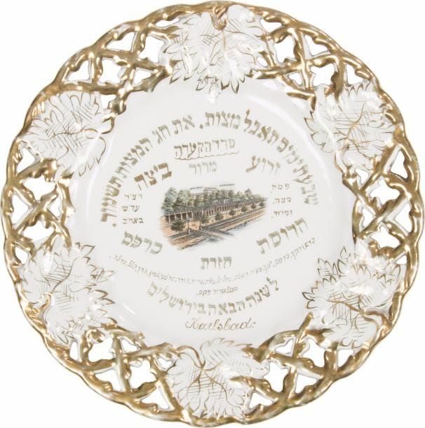 [PESSAH] Plateau de Seder en porcelaine. 
Karlsbad, Empire austro-hongrois, vers 1900. 
Inscriptions hébraïques traditionnelles s’achevant par la phrase qui conclut le rituel de Pessah : l’année prochaine à Jérusalem. L’aile est ajourée et dorée, à décor de feuilles de vignes. 
Diamètre : 27 cm