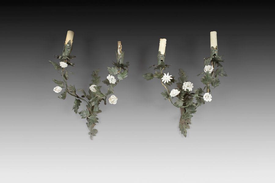Paire d'appliques de trumeau, à deux lumières, en tôle laquée vert à décor de branchages feuillagés soulignés de fleurs en pâte tendre blanche. Travail probablement italien, de la fin du XVIIIe siècle. Hauteur : 36 cm - Largeur : 30 cm