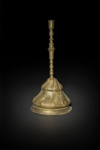 Chandelier aux guirlandes florales, tombak, Turquie ottomane, fin XVIIIe-début XIXe siècle
Chandelier à fût en bronze mouluré en balustre sur large base en cuivre repoussé et doré en dôme en doucine. Décor de feuilles sâz sur l’ensemble. 
Haut. : 47 cm
État : petites enfoncements sur la base et trous pour montage de lampe en trois parties. Fût d’une autre pièce.
Pour d’autres chandeliers en tombak, voir par exemple les catalogues de ventes publiques, Daussy-Ricqlès, 26 février 1990, lot 63 donnant un nom de propriétaire, ou le catalogue  de F.Ricqlès,  6 déc. 1999, n° 472, voir aussi I. Gündag Kayaoglu, Tombak, Disbank, Istanbul, 1992, p.13
A large Ottoman gilt-copper, tombak, candlestick, Turkey, late 18th- early 19th century 