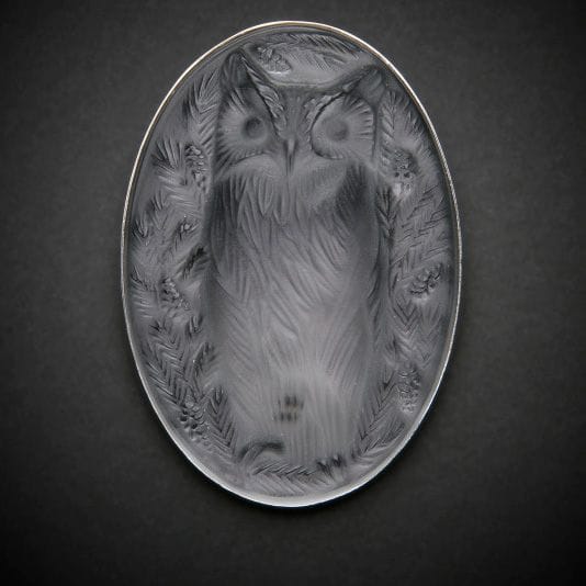 Maison LALIQUE d’après un modèle de Marie-Claude LALIQUE (1935-2003)
Hibou
Broche en cristal moulé-pressé, achevé satiné, sur tain miroir gris. Platine en métal argenté. Signée LALIQUE France au revers de la platine. L. 6,5?cm
