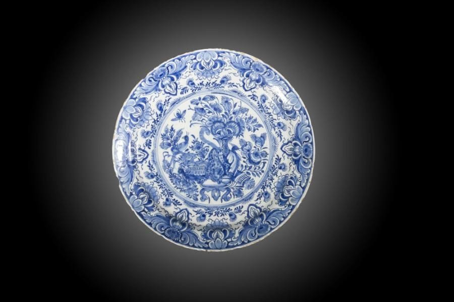 Delft
Plat rond en faïence à décor en camaïeu bleu d’un félin parmi des vases fleuris. 
XVIIIe siècle. 
D. 34 cm 
éclats.