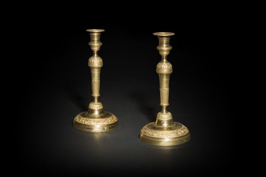 Paire de flambeaux en bronze verni à fût en balustre à arcatures, la base circulaire à frise de rinceaux fleuris et vases dans un entourage de perles.
Époque Restauration (usures)
H : 30,5 cm

