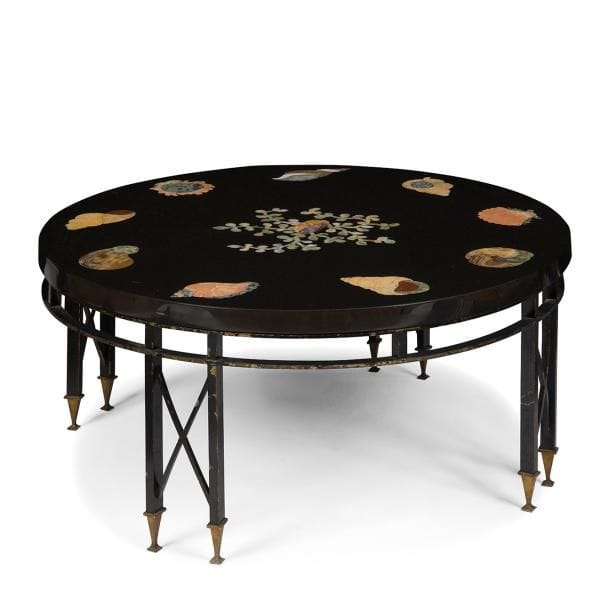 TRAVAIL NÉOCLASSIQUE des ANNÉES 1940 / 50
Coquillages et coraux
Rare table basse circulaire.
Base en bronze, en partie laqué noir, constituée de quatre doubles jambages, aux entretoises en X et reposant sur des pieds en gaine terminés par des patins carrés, réunis par une double ceinture circulaire.
Plateau au riche et précieux décor réalisé en marqueterie de marbre et de pierres dures.
Restaurations et altérations à la laque du piètement.     
Hauteur : 43 cm
Diamètre : 92 cm
