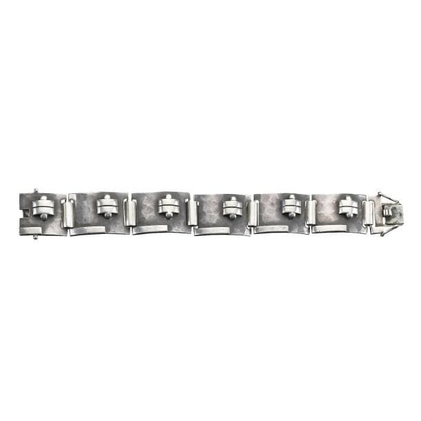 Jean DESPRÉS (1889-1980)
Rare bracelet moderniste articulé en argent.
Les six plaques concaves reçoivent des décors, en applications, de motifs géométriques (barrettes, languettes et sphères) sur fond martelé.
Signé J. DESPRÉS à la pointe au revers de l'une des plaques et porte les poinçons de Maître Orfèvre et de garantie sur le fermoir.
Poids : 70,32 g
Provenance :
Ancienne Collection M. & Mme C. (Magny près d'Avallon - France), œuvre acquise par ces derniers directement auprès de l'artiste.