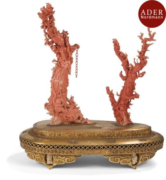 CHINE - XXe siècle
Groupe en corail rose, deux jeunes femmes debout, l’une portant une branche sur laquelle sont posées deux perroquets, accompagnées d’enfants, et tenant des éventails rigides. (Une branche restaurée, petits accidents). 
Hauteur : 36 cm et 29,5 cm
Poids : 1117 grammes et 481 grammes. Socle en métal doré avec des branches de corail blanc.
Provenance : 
Vente Ader-Picard-Tajan, Paris, 12 juin 1972, N°36.
Lot vendu sur folle enchère.
