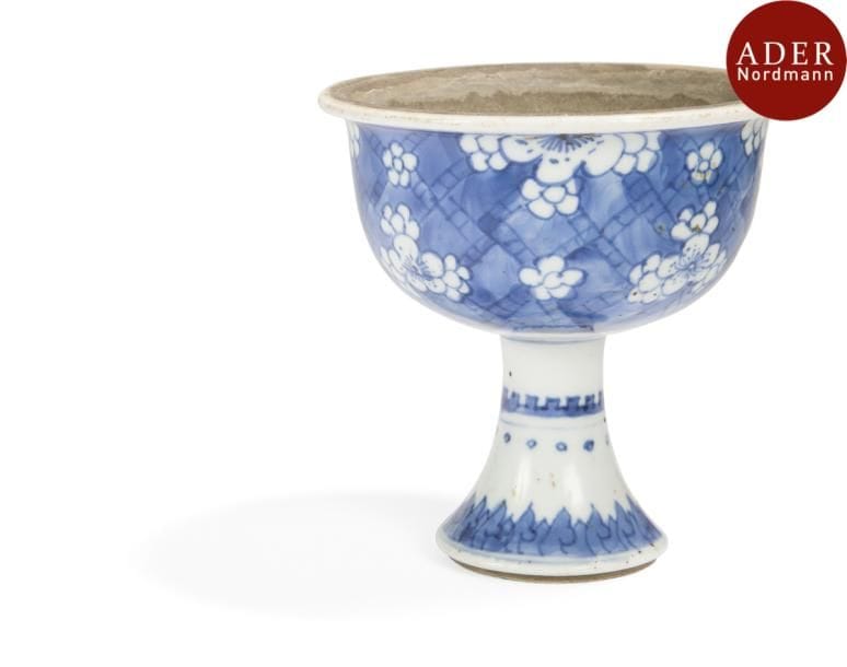 CHINE - XVIIIe siècle
Coupe évasée sur pied en porcelaine à décor en bleu sous couverte de fleurs de pruniers sur fond de motifs géométriques. (Éclat au pied).
Hauteur : 11,2 cm