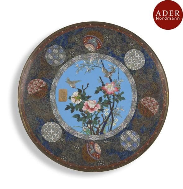 JAPON - Époque MEIJI (1868 - 1912)
Paire de plats en cuivre et émaux cloisonnés à décor d’oiseaux parmi les pivoines sur fond turquoise, l’aile ornée de médaillons de motifs géométriques et de papillons.
Diamètre : 37 cm