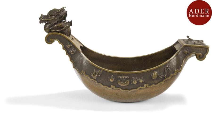JAPON - Époque MEIJI (1868 - 1912)
Vase à suspendre en bronze à patine brune en forme de barque ciselé des attributs des sept dieux du bonheur. La proue en forme de dragon. (Manques).
Longueur : 50 cm