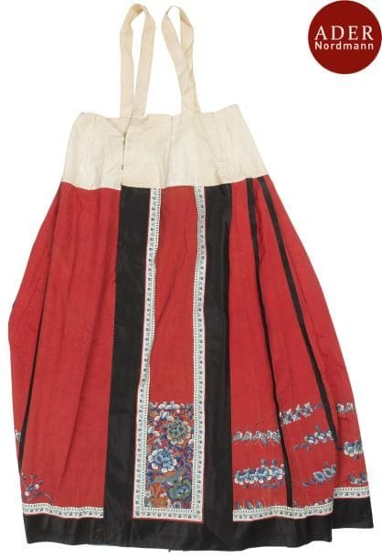 CHINE - XIXe siècle
Jupe (Mamianqun) en tissu rouge, à décor brodé aux fils dorés et polychromes de pivoines et papillons.
Doublée en soie bleue. 
Hauteur : 101 cm
(Accidents)