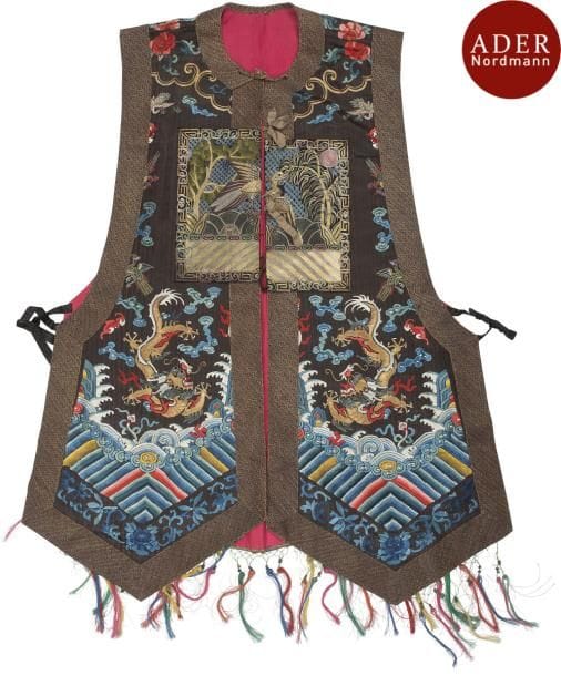CHINE - XIXe siècle
Gilet de femme du quatrième rang civil (Xia pei) en soie brune à décor brodé aux fils d’or et polychrome de dragons et grues parmi de nuages, le carré orné d’un canard mandarin au-dessus de vagues. Orné des franges multicolores. 
Doublé en soie rouge.
Hauteur : 103 cm
(Retouché, accidents)