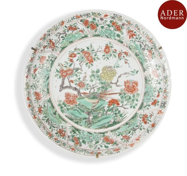CHINE - Époque KANGXI 
(1662 - 1722)
Grand plat en porcelaine émaillée polychrome de la famille verte à décor de faisan perché sur un rocher et branches fleuries. (Égrenures et fêlures). 
Diamètre : 47,2 cm
