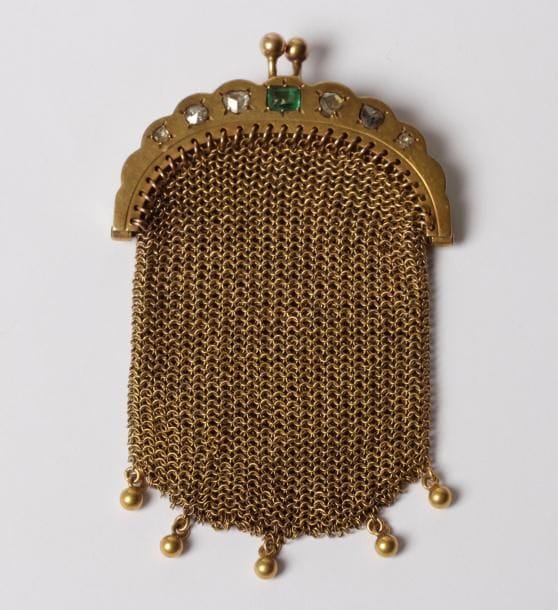 Porte-monnaie en tricot d’or 18K (750‰), le fermoir agrémenté d’une émeraude et de diamants taillés en roses.
Travail français du début du XXe siècle.
Hauteur : 7,5 cm environ. Poids brut : 43,2 g