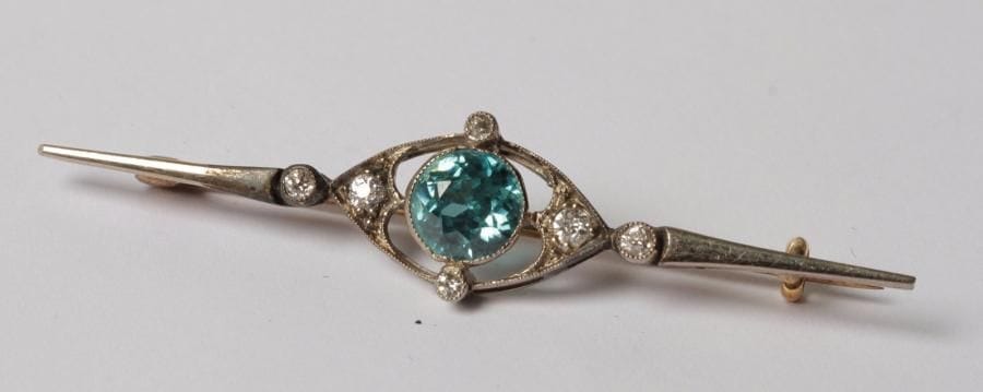 Broche fuseau en or 18K (750‰) et argent, ornée d’une pierre bleue, agrémentée de petits diamants.
Travail du début du XXe siècle.
Longueur : 5,1 cm environ. Poids brut : 3,2 g