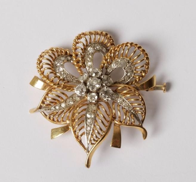 Broche fleur en fils d’or 18K (750‰) et platine, sertie de diamants de taille ancienne.
Travail français des années 1960.
Dimensions : 4 x 4,2 cm environ. Poids brut : 13,5 g