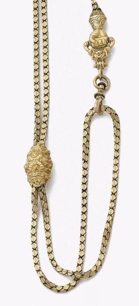 Chaîne de montre de gousset en or jaune 18K (750‰), articulée de petits maillons géométriques imbriqués, le fermoir sculpté en main gantée, ornée d’un coulant mobile ciselé de fleurs et feuillages.
Travail français du XIXe siècle. Poids : 36,4 g