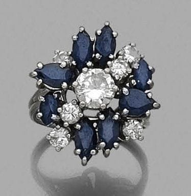 Bague en fils d’or gris 18K (750‰), ornée d’un diamant pesant environ 0,70 ct semé dans des saphirs navettes et poires, agrémentée de diamants.
Travail français des années 1960.
Tour de doigt : 50. Poids brut : 6,6 g