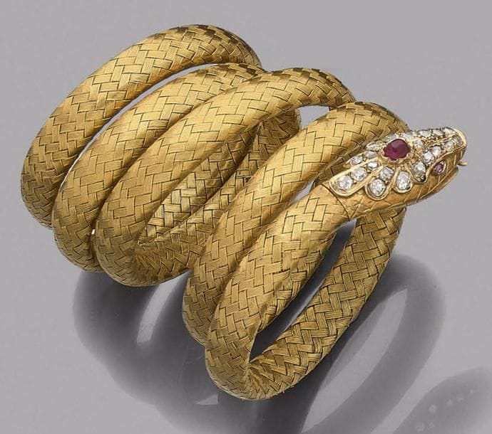 Bracelet armille en or 18K (750‰) tressé formant un serpent, la tête sertie de diamants taillés en roses, sommée d’un rubis cabochon, les yeux piqués d’un saphir rose.
Travail français de la fin du XIXe siècle.
Poids brut : 53,3 g
(déformations)