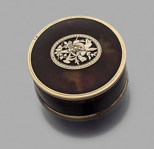 Boîte ronde en écaille et cerclage en vermeil portant en son centre un médaillon ovale représentant des instruments de musique en vermeil rapportés. Léger accident à l’écaille en bordure intérieure.
FRANCE, XIXe siècle
Poinçon au sanglier et poinçon d’orfèvre illisible
Poids brut : 61,49 g - diamètre : 7 cm - hauteur : 3,7 cm