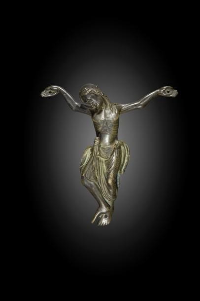 Christ en bronze à patine sombre, fonte creuse. 
Tête inclinée sur l’épaule droite avec restes de couronne, visage aux yeux clos, chevelure aux longues mèches tombant sur les épaules, barbe courte, bras au-dessus de l’horizontale, important périzonium avec chutes latérales et nœud central proéminent découvrant le genou droit et enveloppant le genou gauche, jambe gauche verticale et fléchie avec pied en légère rotation interne, jambe droite fléchie et tournée latéralement avec pied en rotation externe reposant sur le gauche.
France ou Allemagne, vers 1270 / 1300 
H : 16,2 cm, L : 15,5 cm
Soclé