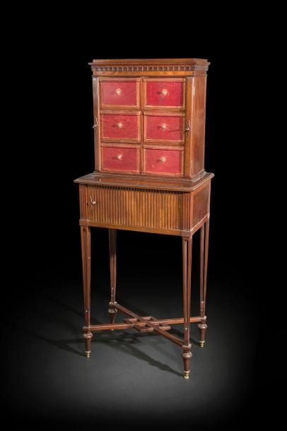 Cartonnier en acajou mouluré, les pieds ajourés en gaine réunis par une entretoise, ouvrant à un rideau ; la partie supérieure à six cartons de maroquin rouge doré aux petits fers.
Dans le goût de Martin-Guillaume Biennais.
Premier tiers du XIXe siècle (accidents et manques).
H : 154 cm, L : 60 cm, P : 39 cm 


Un Meuble de voyage comparable par sa structure générale, portant la plaque de Biennais, est illustré dans D. Ledoux-Lebard, Le mobilier français du XIXe siècle, Paris, 2000, p. 86. La forme du piétement évoque également un dessin de l’album La mésangère, publié au tout début du XIXe siècle (voir U. Leben, Molitor, Saint Rémy en l’Eau, 1992, p. 106).