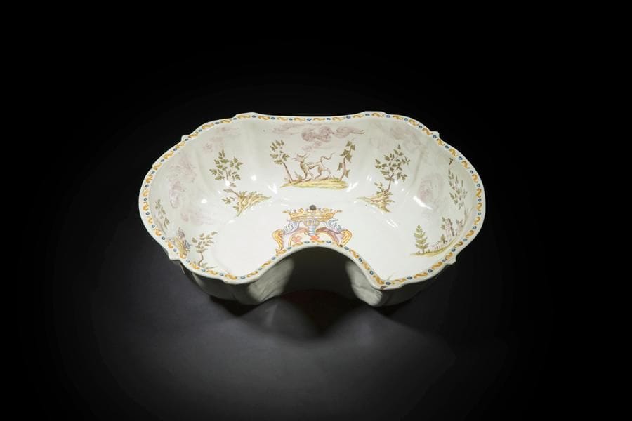 Italie du Nord
Bassin ovale à bord contourné échancré en faïence à décor polychrome au centre d’armoiries dans un écu sous un heaume et une couronne et sur le bord d’animaux fantastiques, soldat et forteresse sur des tertres encadrés d’arbustes.
XVIIIe siècle. 
L. 37 cm
Légères fêlures, petits éclats et percé pour l’accrochage