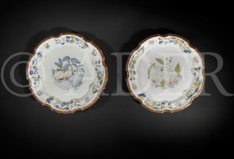 Nove di Bassano
Deux assiettes à bord contourné en faïence à décor polychrome de fruits sur des rinceaux rocaille au centre et de tiges fleuries sur l’aile.
XVIIIe siècle. 
D. 23 cm
Égrenures