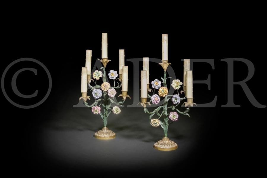 Lustre à six lumières et paire de candélabres, en tôle peinte et fleurs de porcelaine, les candélabres à cinq lumières reposant sur une base en bronze verni.
Fin du XIXe siècle (accidents et manques).
H (lustre) : 67 cm ; H (candélabre) : 40 cm