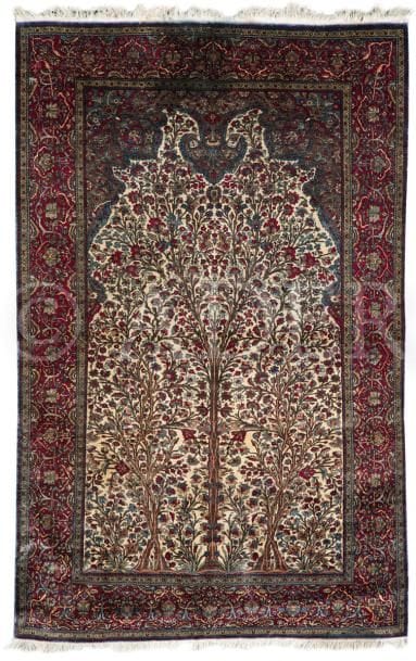 KECHAN en soie (chaîne, trame et velours)
Très fin tapis à décor de trois arbres de vie inscrits dans un mirhab sur un fond ivoire, bordure rubis à guirlandes de fleurs.
Coulé.
198 x 125 cm