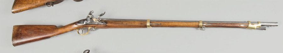 Fusil d'artillerie à silex modèle 1816. Canon rond poinçonné au tonnerre (piqûres), daté « 1824 ». Platine marquée « ... de Maubeuge ». Garnitures en laiton. Baguette en fer. Crosse à joue en noyer (refrappée). Plaque de couche gravée « Don patriotique ». E.M. (couvre bassinet postérieur, réparation au chien)