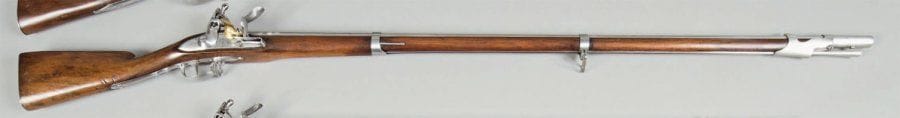 Fusil d'Infanterie à silex Modèle 1777. Canon rond à pans au tonnerre avec poinçon. Queue de culasse marquée « Mle 1777 » (regravée). Platine gravée « St-étienne », frappée 91 et J sous couronne, marquée à l'intérieur Chenevier, bassinet en laiton. Garnitures poinçonnées et baguette en fer. Embouchoir à ressort. Crosse à joue en noyer verni. B.E. (Reconditionné, gravure retouchée) Longueur : 152,8 cm. Canon : 113,6 cm