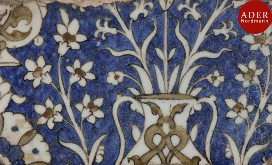 Trois carreaux de revêtement, Syrie ottomane, Damas, XVIIe siècle
Deux rectangulaires et un carré, en céramique siliceuse, à décor polychrome sur fond bleu et sous glaçure transparente. Parties de composition : haut de vase fleuri, médaillon et arabesques végétales, et médaillon floral sur fond vert ceinturé de feuilles sâz. 
Dim. : 13,5 x 19 cm ; 12 x 20 cm ; 26 x 21,2 cm 
État : bords et dos égalisés.
Three Damascus pottery tiles, Ottoman, Syria, 17th century