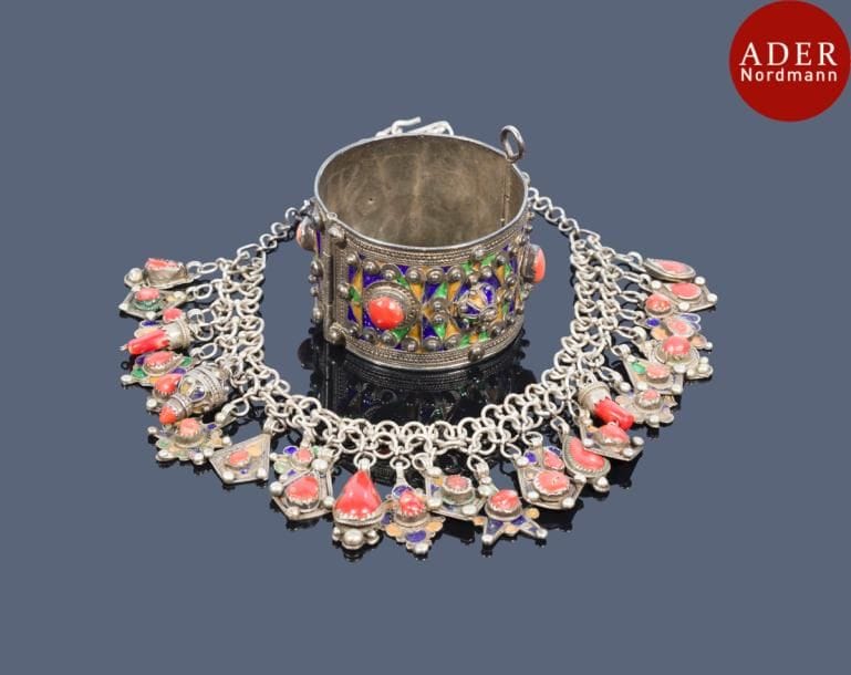 Collier azrar et bracelet, Algérie, Grande Kabylie, Beni Yenni, XXe siècle
Sur un assemblage de deux chaînettes, une série de pendeloques variées en argent, émaillées et perlées, serties de corail ; - bracelet à charnière émaillé polychrome orné de cabochons de corail.
Long. collier ouvert : 41 cm ; diam. bracelet : 5,8 cm ; PB  : 185 g
An azrar necklace and a bracelet, Algeria, Grand Kabylie, Beni Yenni, 20th century 