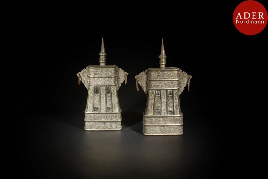 Grande boîte à poudre, Afrique du nord, Afrique du Nord, XIXe siècle
Boîte composée d’un corps tronconique à oreilles en khema, laiton et métal argenté, bouchon en forme de minaret. Elle est décorée en application sur les deux faces, comme sur les côtés bombés et sur les oreilles de plaques de cuivre argentées découpées ornées de rinceaux floraux curvilignes, gravés et repoussés. 
Haut. : 48, 5cm
A large powder flask, North Africa, probably Algeria,19th century