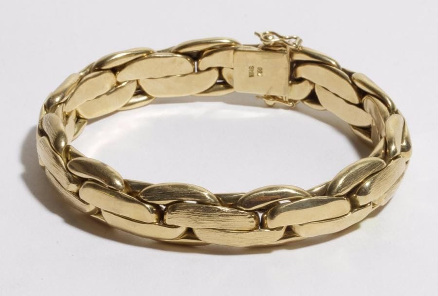 Bracelet souple en or 18K (750) articulé de maillons oblongs lisses ou guillochés. 
Poids : 42 g