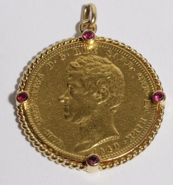 Pendentif en or 18K (750) orné d'une pièce de 100 lires 1840, la monture agrémentée de 4 pierres rouges. 
Poids brut : 36,9 g