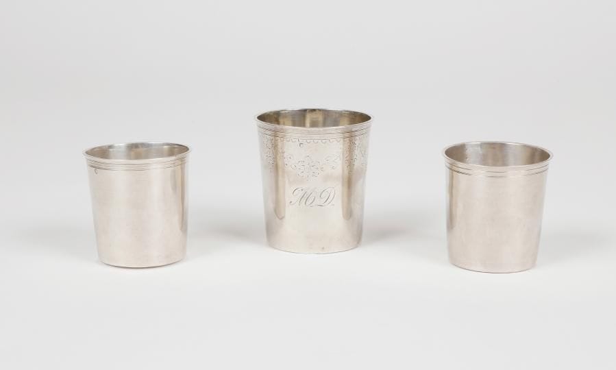 Trois timbales à fond plat en argent moulurées de filets, pour deux non gravées, pour la troisième ciselée d'un décor fleuri et chiffrée MD.PARIS 1819 - 1838Orfèvre : pour deux Théodore TONNELIER, le troisième non identifié
Poids : 179 g - hauteur : 7,9 cm - 6,6 cm x 2