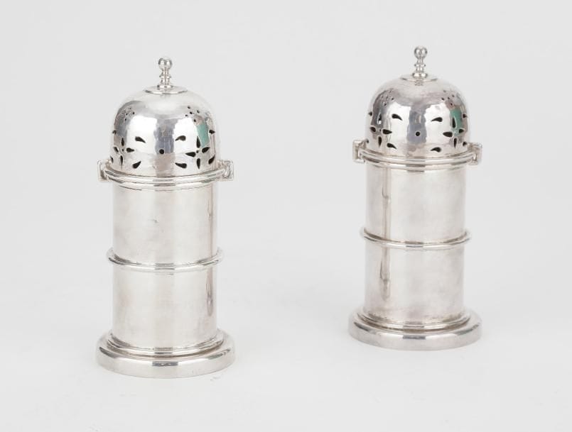 Paire de poudreuses en métal, le fût rond, le dôme repercé de lames, le bouton en pirouette et l'ouverture à baïonnette.Hauteur : 16,3 cm