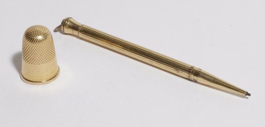 Dé à coudre en or 18K (750). 
Poids : 3,7 g. 
On joint un porte-mine en métal doré.