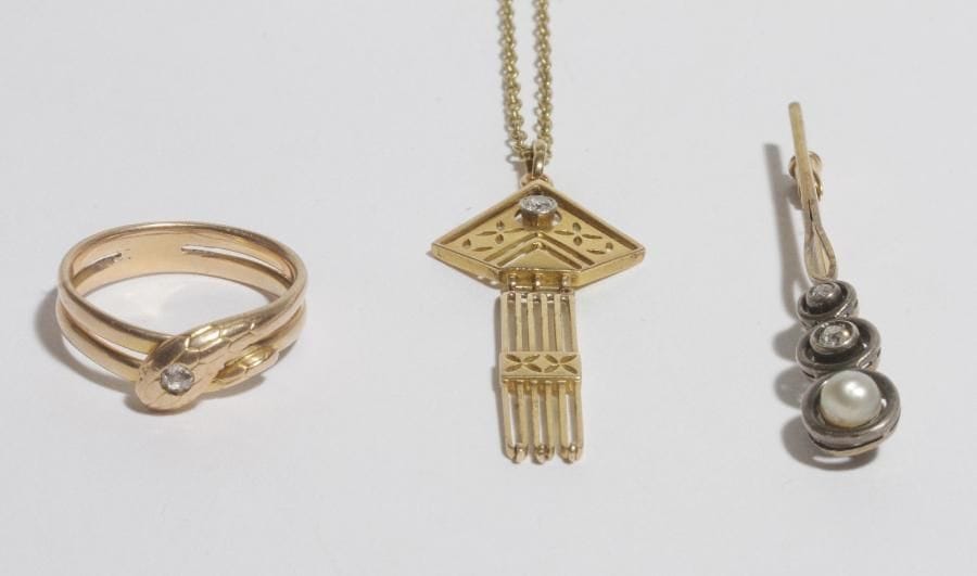 Lot de 3 bijoux en or 18K (750) : une bague serpent, l'œil serti d'une rose; une broche agrémentée de petites roses; un pendentif (14K) de forme losangique serti d'une rose coulissant sur une chaîne en or. 
Poids brut : 16 g (chocs)