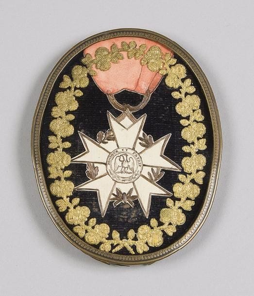FRANCE
« Légion d’Honneur du Ier type. »
Encre sur papier découpé, rehaussé sur les bords de cheveux, pourtour garni de guirlandes de fleurs dorées.
Dans un cadre ovale en bronze. 
XIXe siècle. 
13 x 10 cm